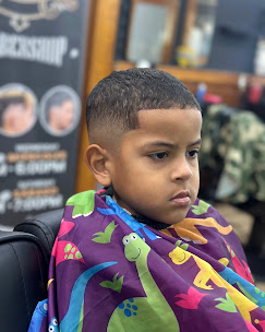 Young client getting a kids haircut in a dinosaur cape at Shaddai Barbershop, Dunnellon FL